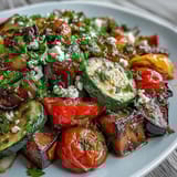 A close-up of Roasted Mediterranean Greek Vegetables topped with crumbled feta, fresh parsley, and glistening lemon juice.
