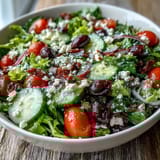 This vibrant Mediterranean Green Salad Bowl features sliced cucumbers, Kalamata olives, and a tangy Greek dressing.