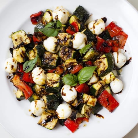 Golden caramelized vegetables glisten under a sweet balsamic drizzle on this vibrant Roasted Veggie Caprese Salad, served on a rustic platter.