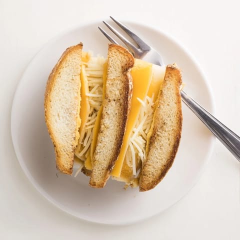 Freshly cooked Triple Cheese Sourdough Grilled Cheese rests on a wooden cutting board, ready to pair with a steaming bowl of tomato soup.
