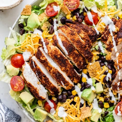 A vibrant Crunchy Taco Chicken Salad with seasoned chicken, crisp romaine, black beans, and corn, topped with creamy dressing.