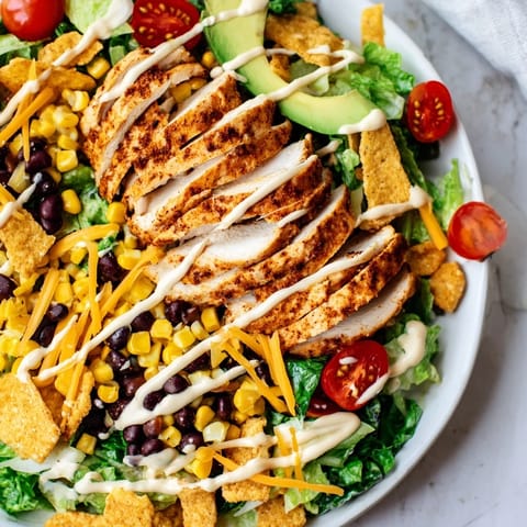 Hearty Tex-Mex Crunchy Taco Chicken Salad featuring tender chicken, avocado, cheddar cheese, and crunchy taco shell pieces.