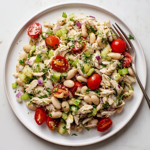 A bowl of Lemony White Bean Chicken Salad with juicy cherry tomatoes and fragrant dill, ready to serve as a refreshing, protein-packed main dish.