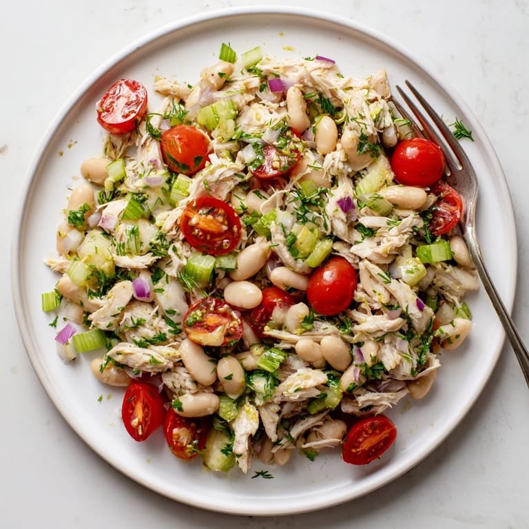 A bowl of Lemony White Bean Chicken Salad with juicy cherry tomatoes and fragrant dill, ready to serve as a refreshing, protein-packed main dish.