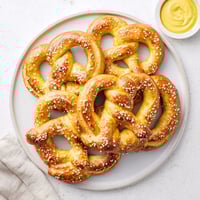Freshly baked golden Soft Pretzels dusted with coarse salt, served warm with spicy brown mustard.